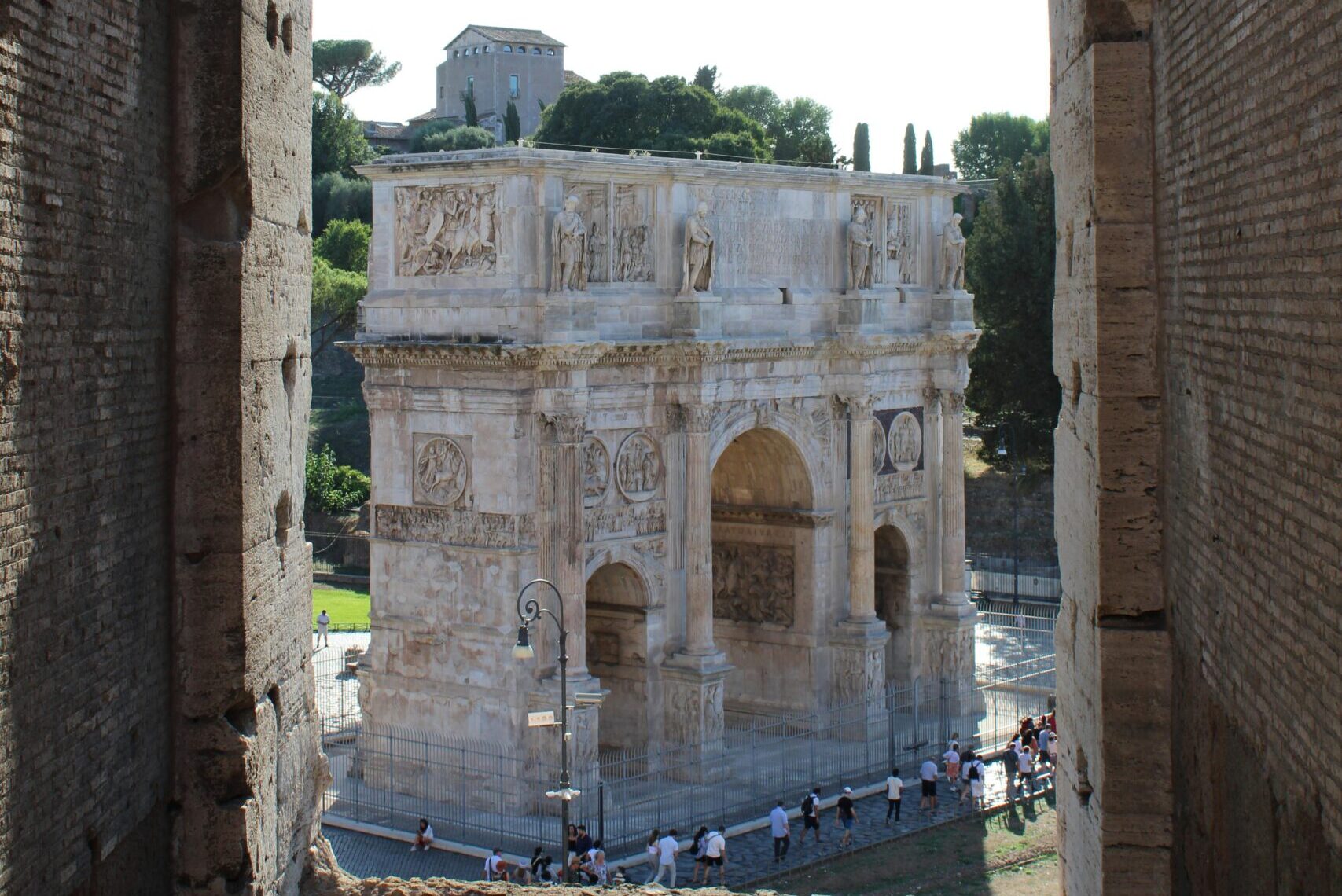 View of the Arch of Constantine through an ancient stone arch in Rome.